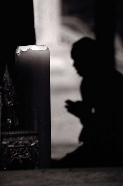 backlit silhouette of a monk praying