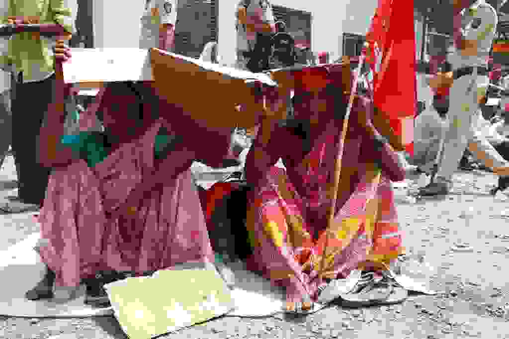 Two women sitting at Azad maidanIn Mumbai, covering their heads with cardboard boxes in the blistering heat.